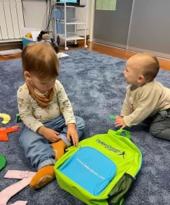 dvije bebe na podu sa ruksakom